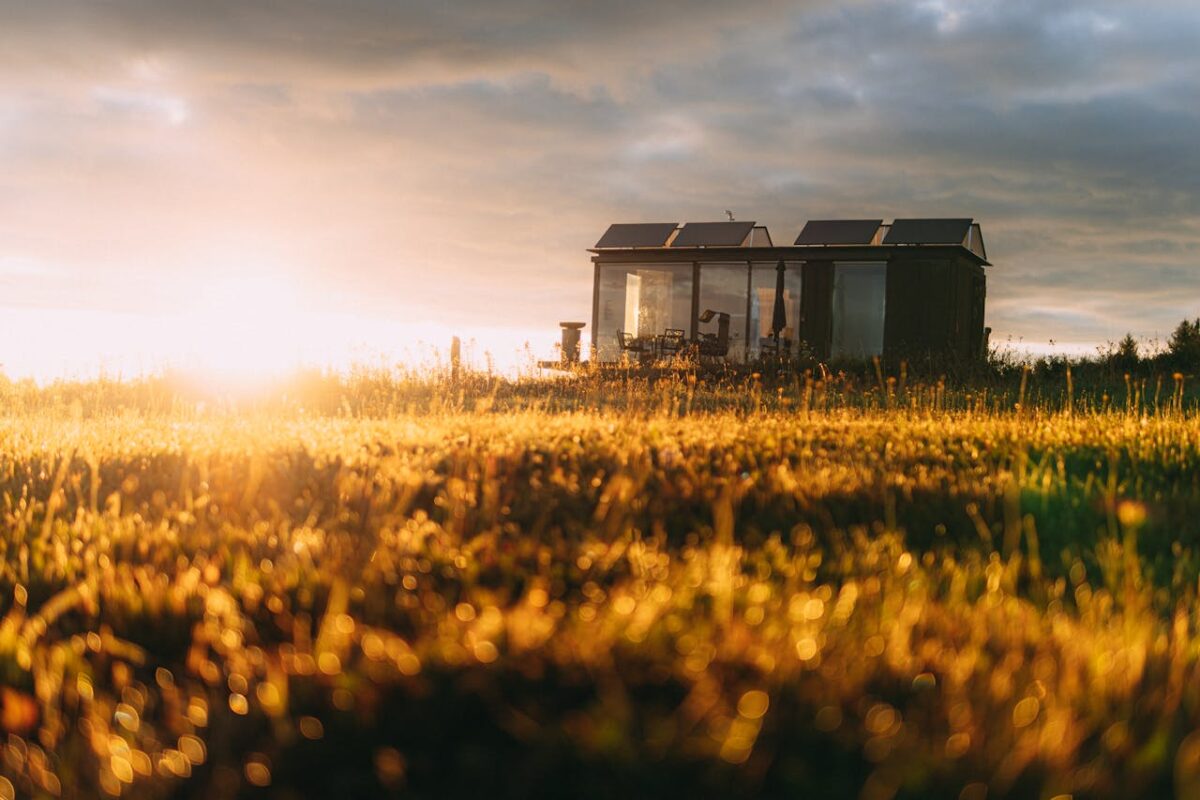 A picturesque tiny house with solar panels in a golden field during sunset, capturing eco-friendly living.